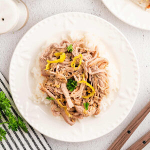 Slow cooked shredded pork roast on a serving plate on a table.