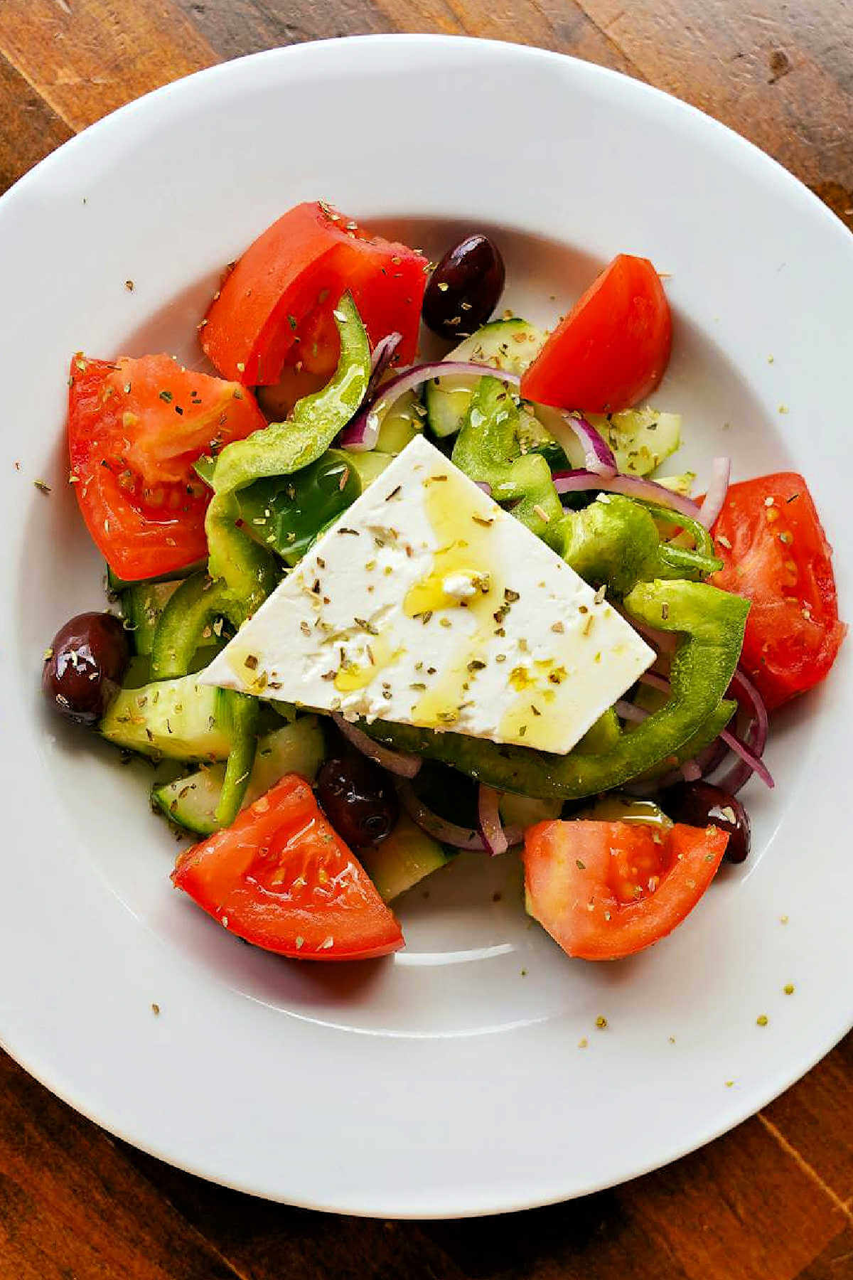 Greek Salad with Dressing on a plate on a table.