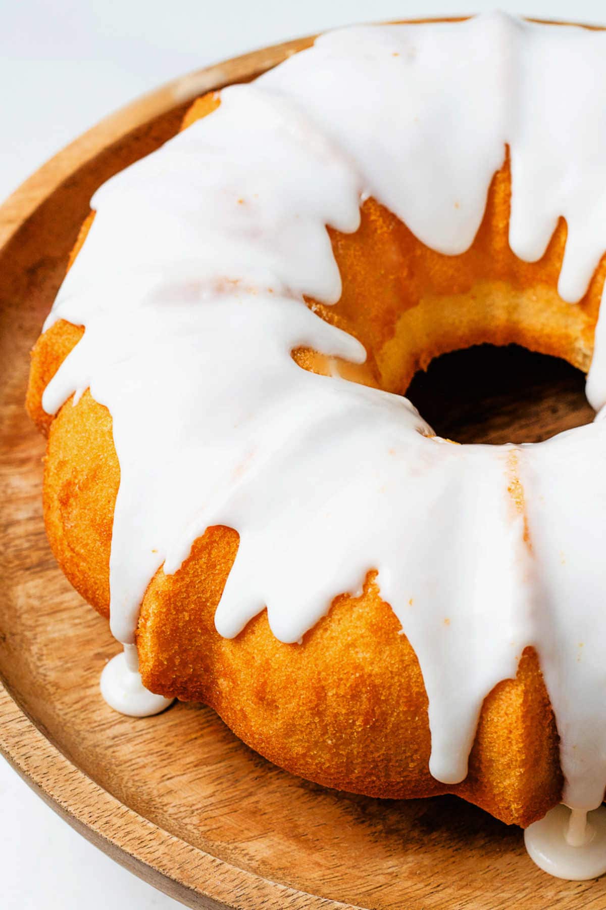 Lemon glaze dripping of a bundt cake onto a cake stand.