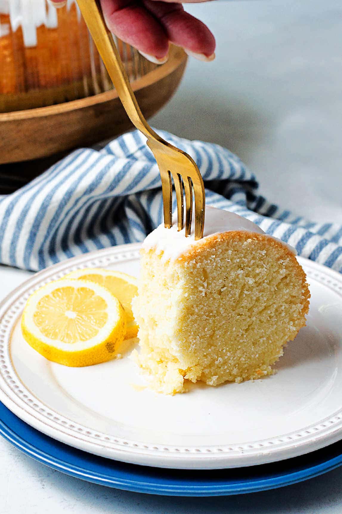 A fork cutting through a piece of pound cake on a plate.