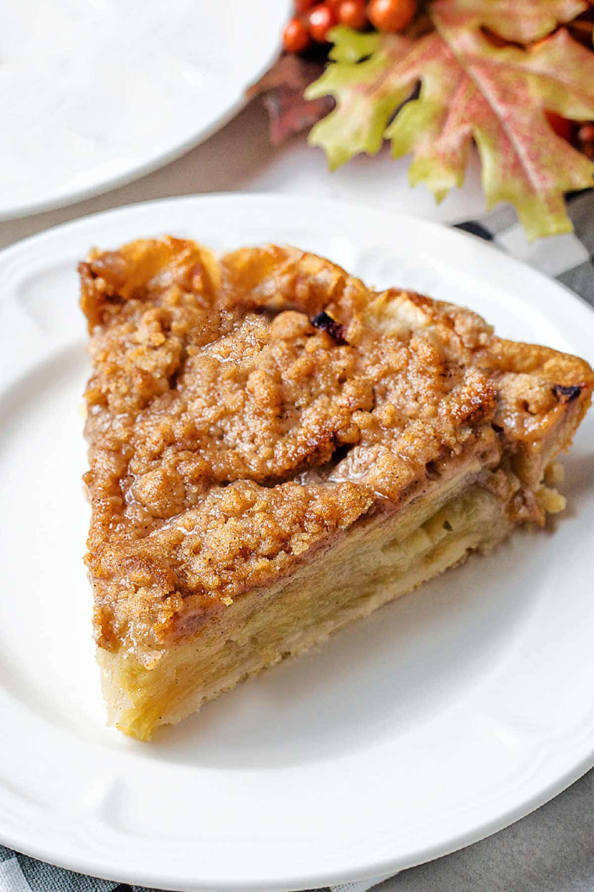 A slice of Dutch Apple Crumble Pie on a plate on a table.