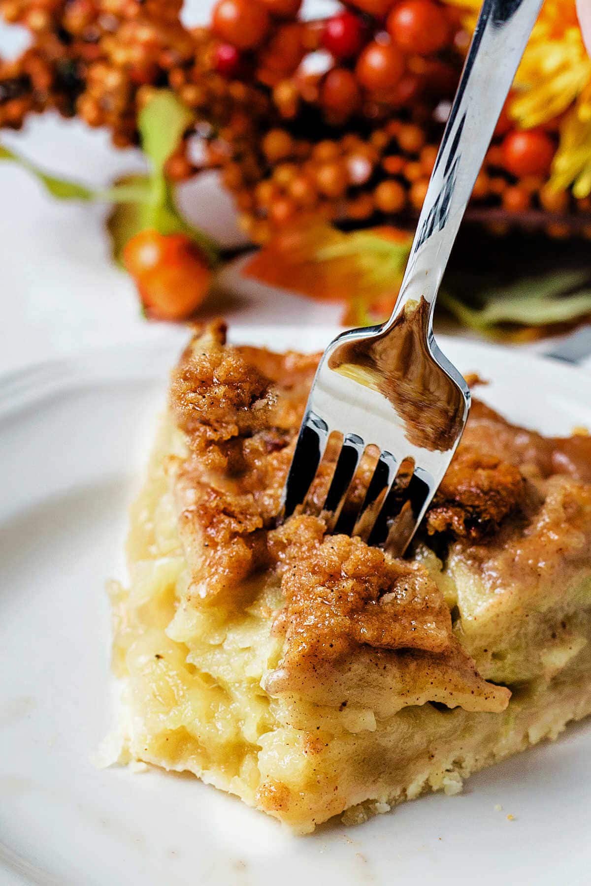 A fork piercing into a piece of pie on a plate.