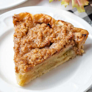 A slice of Dutch Apple Crumble Pie on a plate on a table.