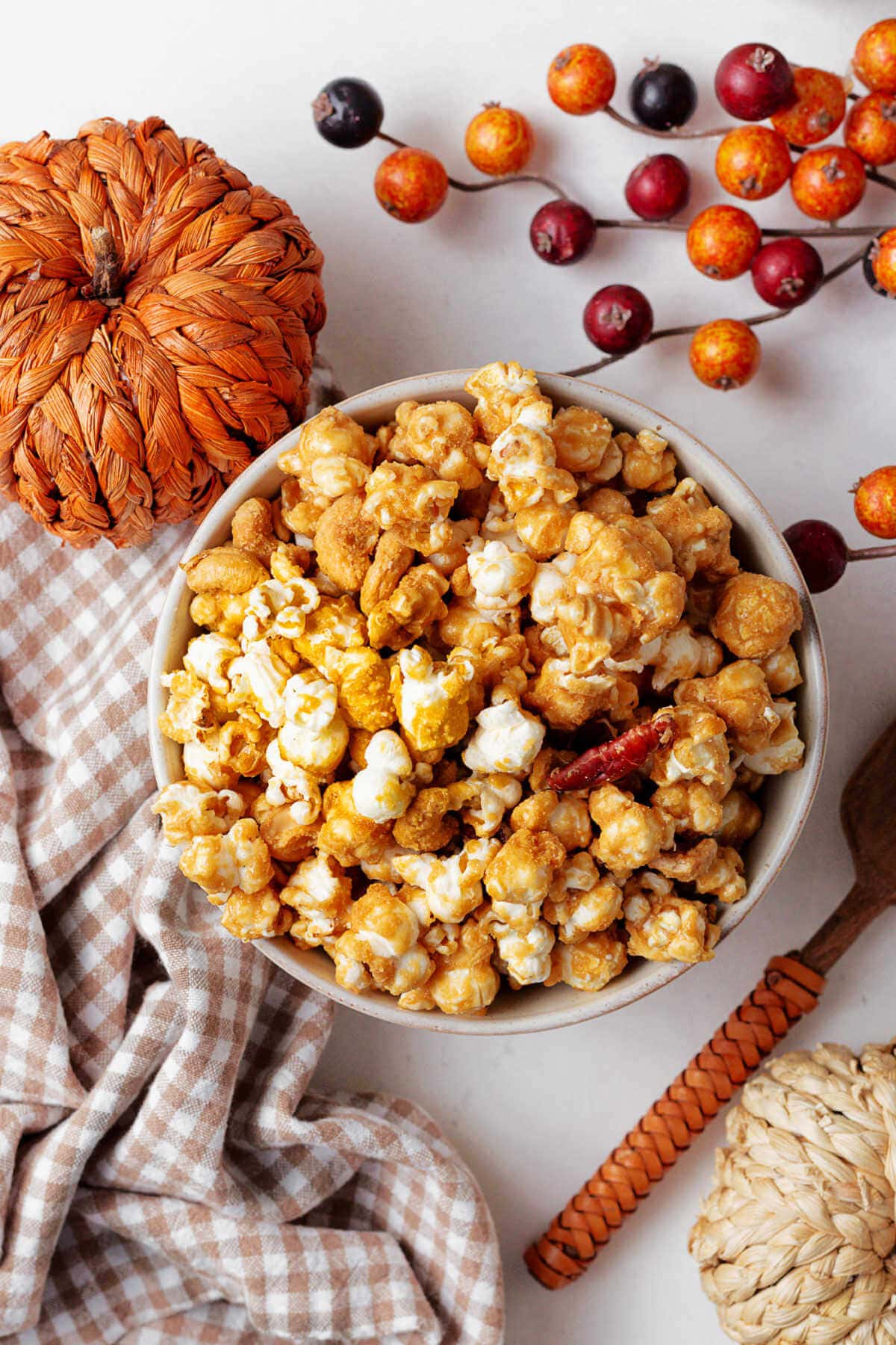 Homemade caramel corn with pecans and cashews in a bowl on a table with fall decor.