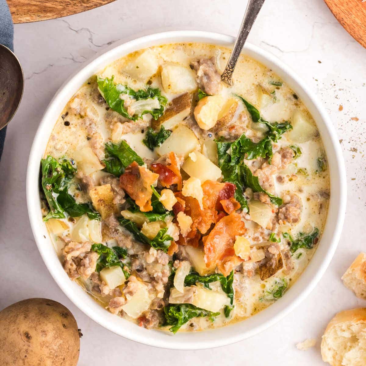 A bowl of Olive Garden Zuppa Toscana soup on a table with a spoon.