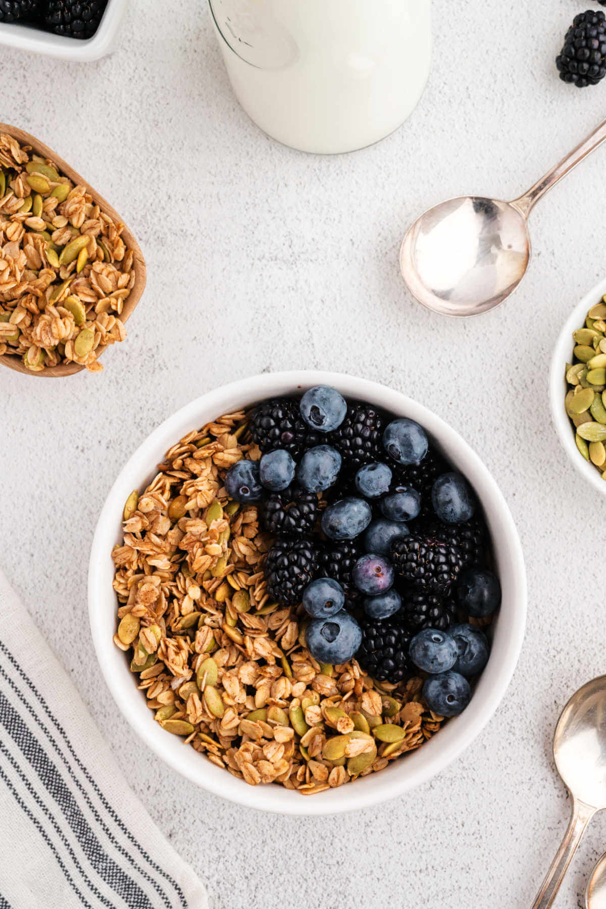 Cinnamon Maple Granola in a bowl with fresh blueberries and blackberries on a table.