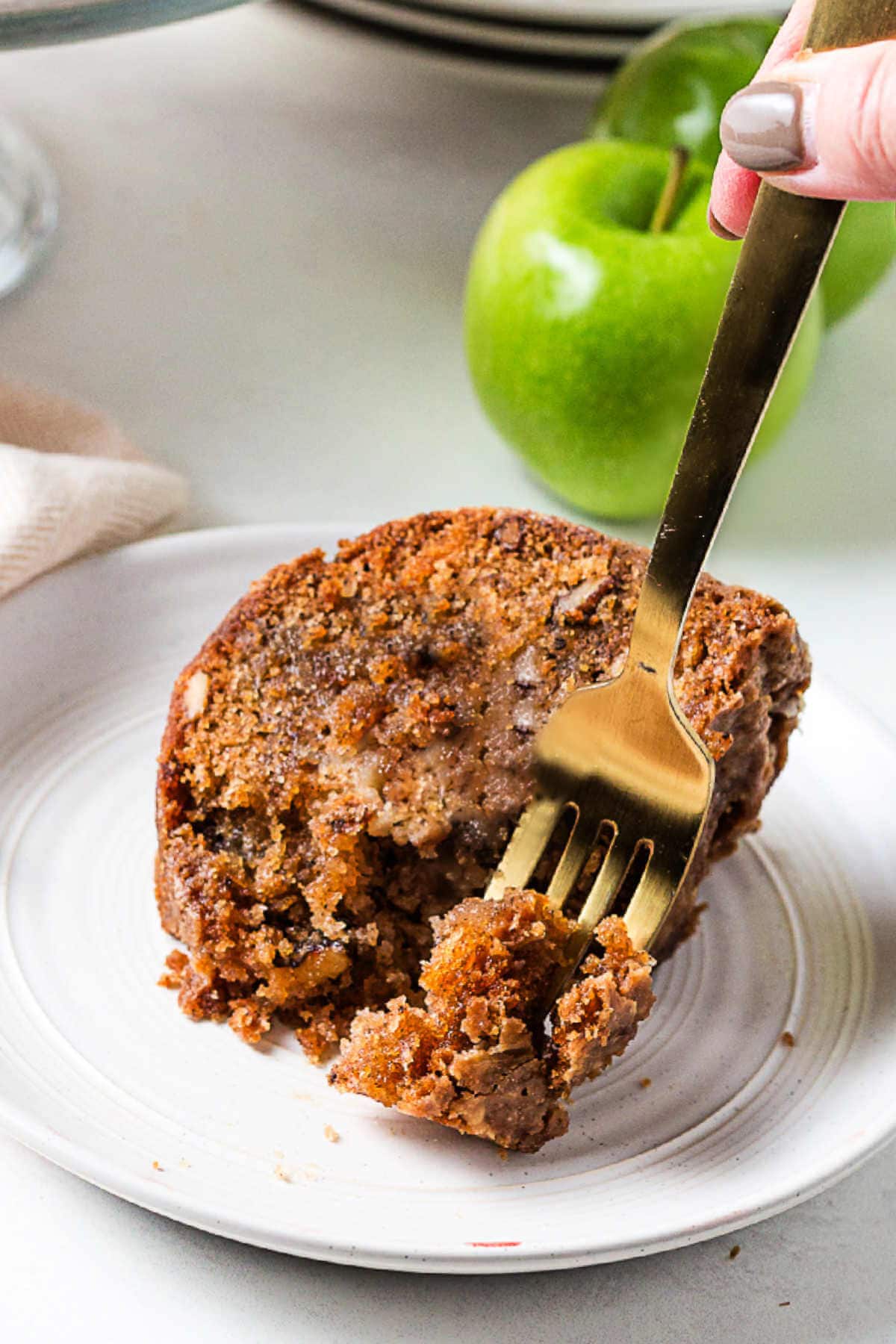 A fork piercing a slice of cinnamon apple bundt cake.