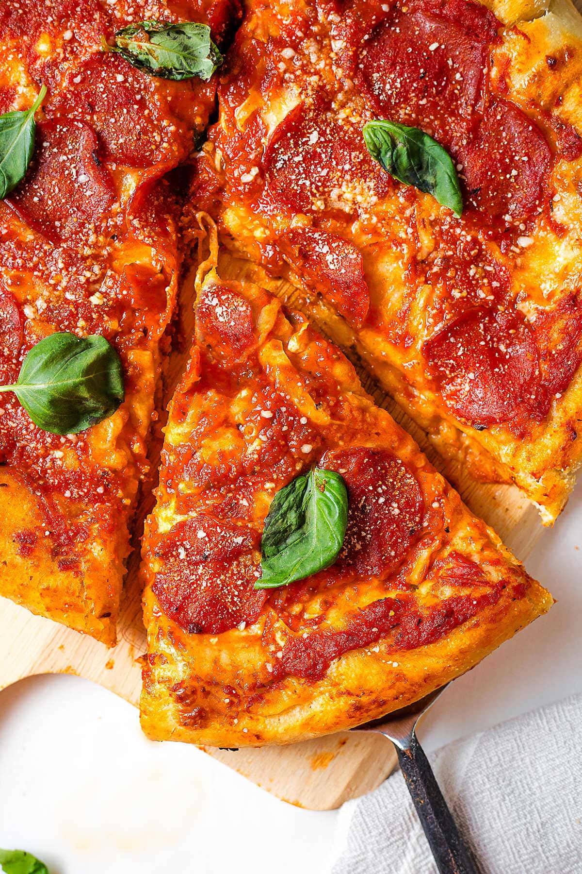 Pepperoni pizza cut into slices on a pizza peel on a table.