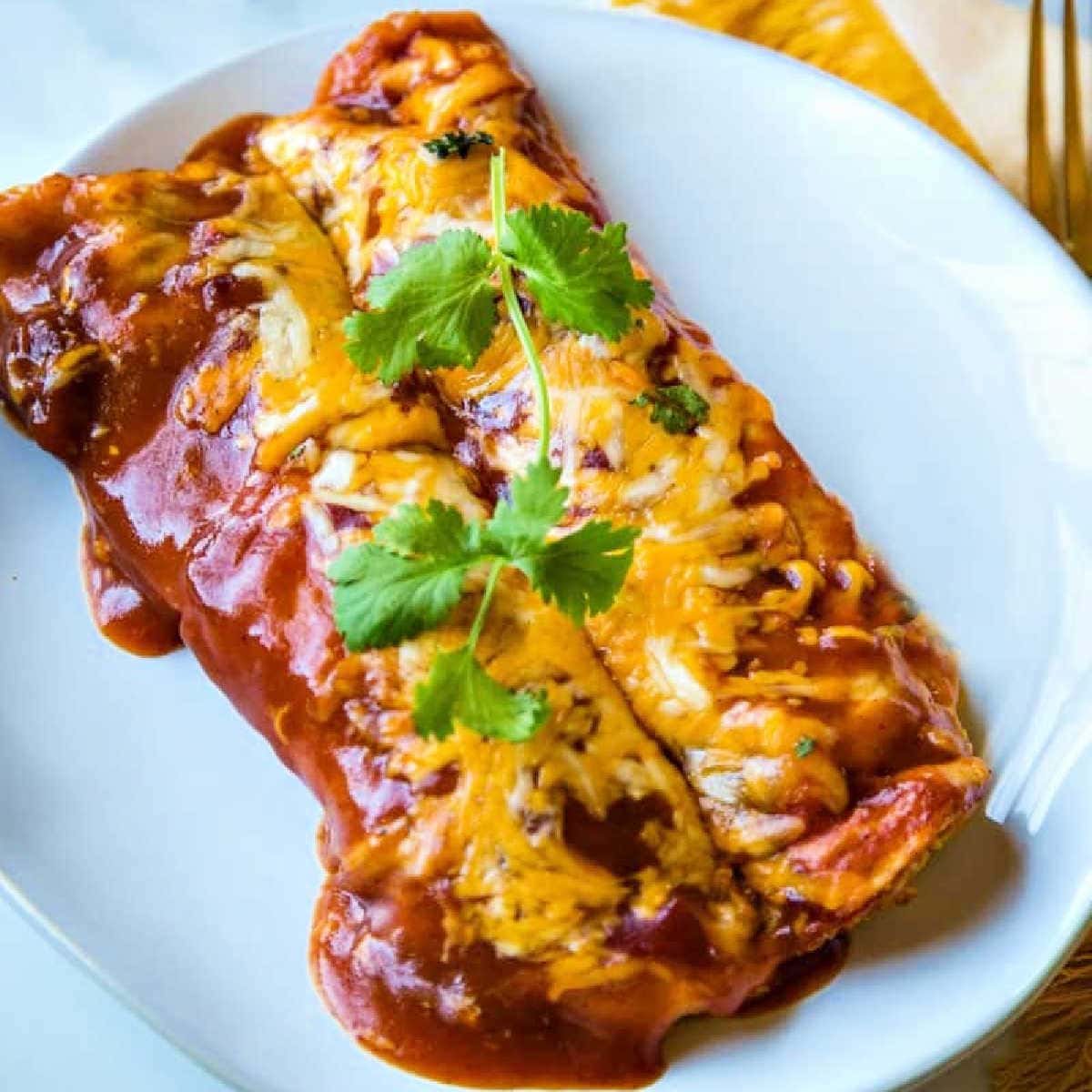 Two chicken and cheese enchiladas on a serving plate garnished with cilantro.