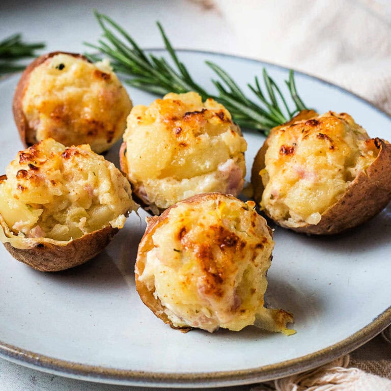 Stuffed Potato Bites on a plate with a sprig of rosemary on a table with a linen napkin.