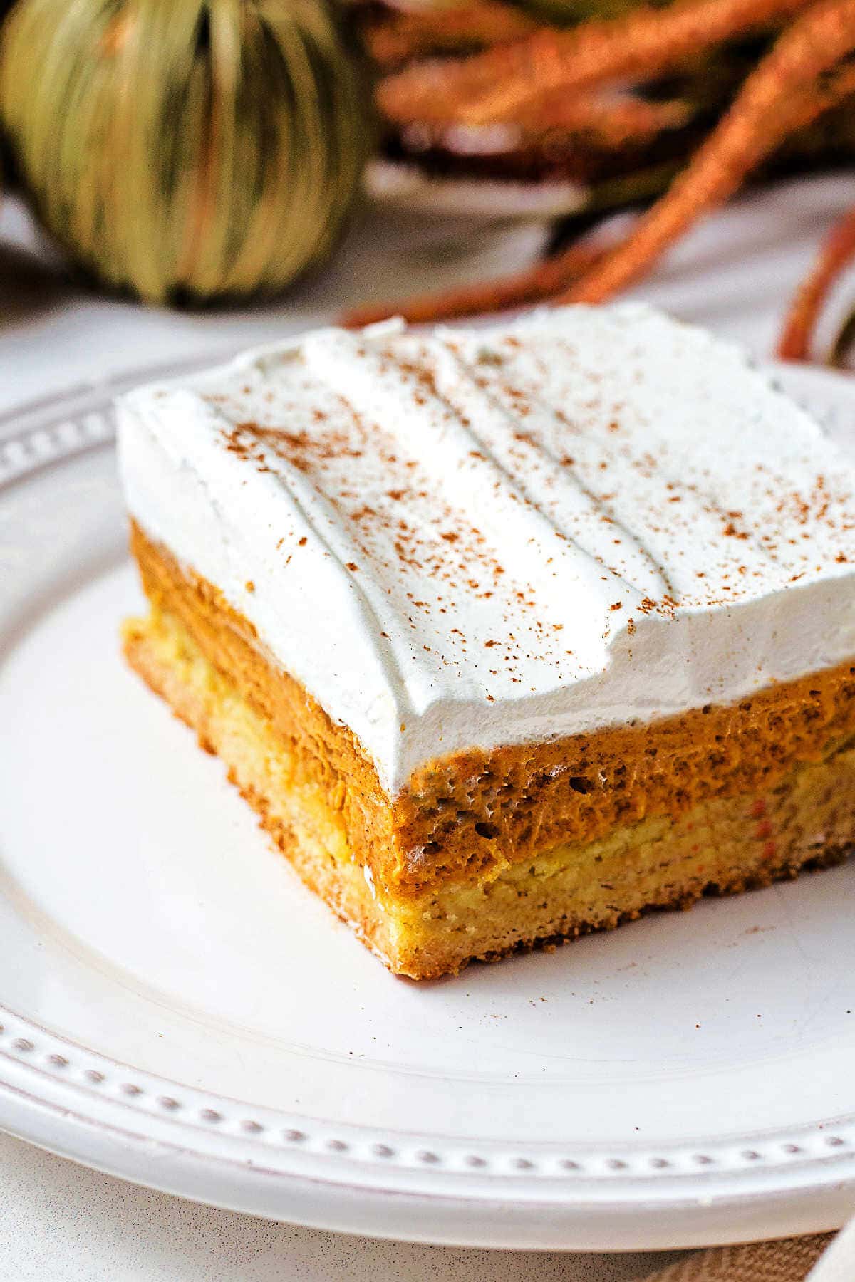 A side profile of pumpkin dessert bars layers on a plate.