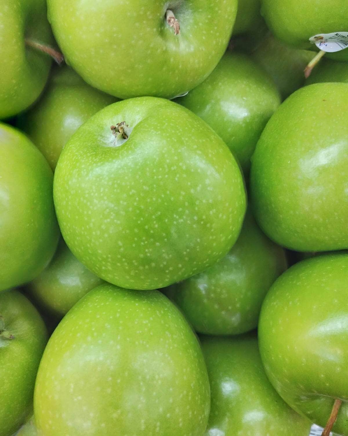 A pile of green granny smith apples.