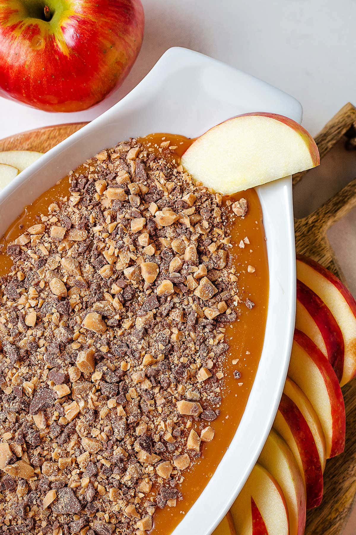 Caramel Apple Dip on a table with an apple slice dipped into the corner of the dip.