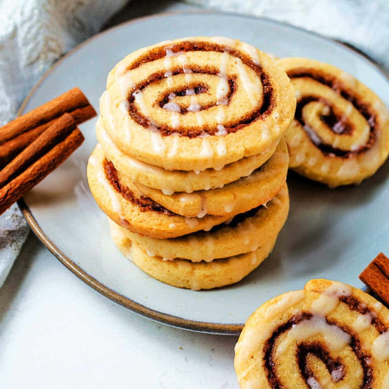 Cinnamon Roll Cookies stacked on a plate with a napkin in the background on a table.