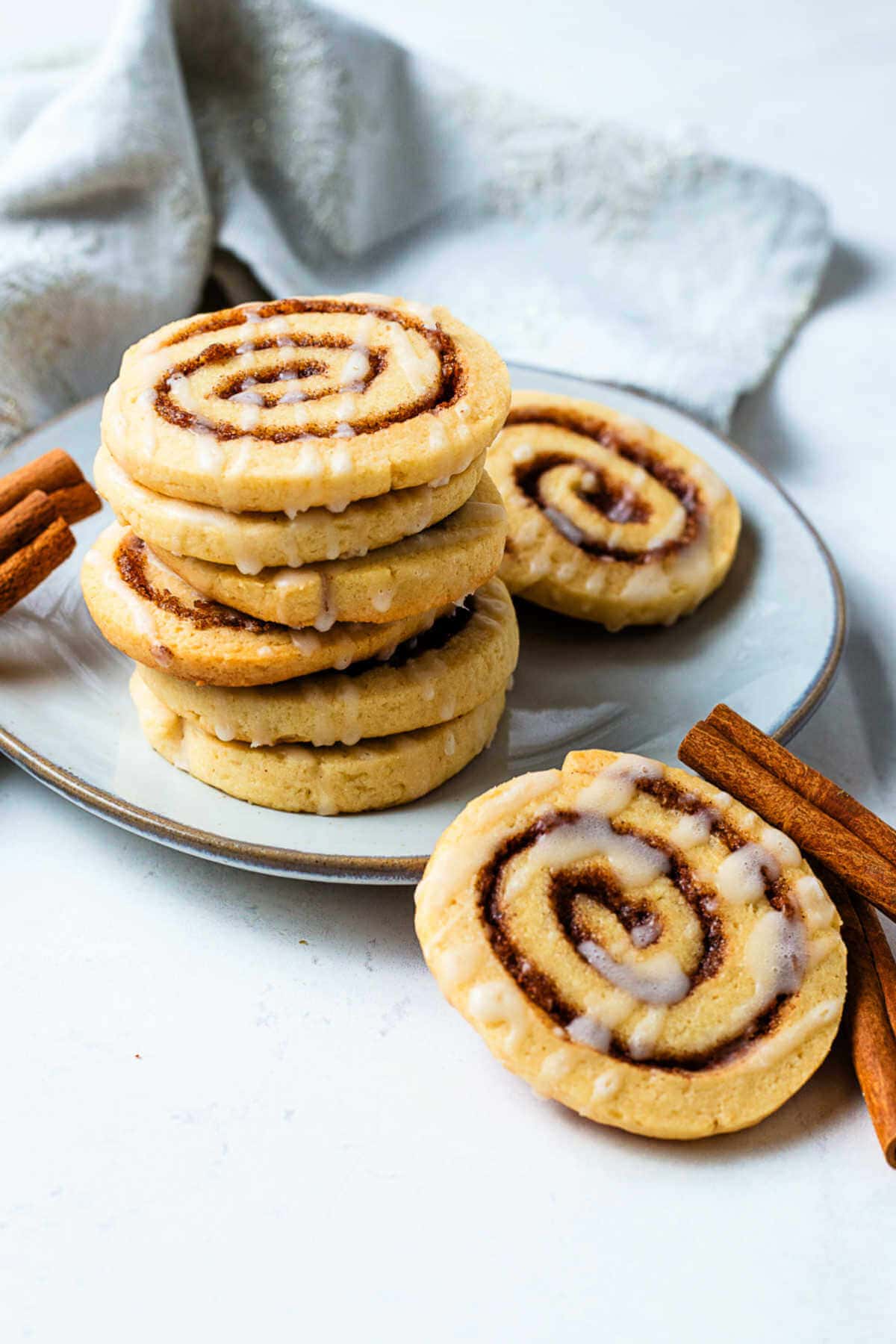 Cinnamon Roll Cookies stacked on a plate with a napkin in the background on a table.