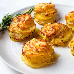 Potaqto Stacks on a serving plate with a sprig of rosemary on a table.