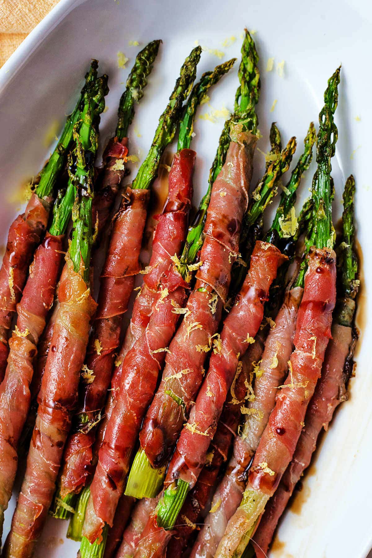 Close up image of asparagus wrapped with prosciutto and drizzled with balsamic vinegar.