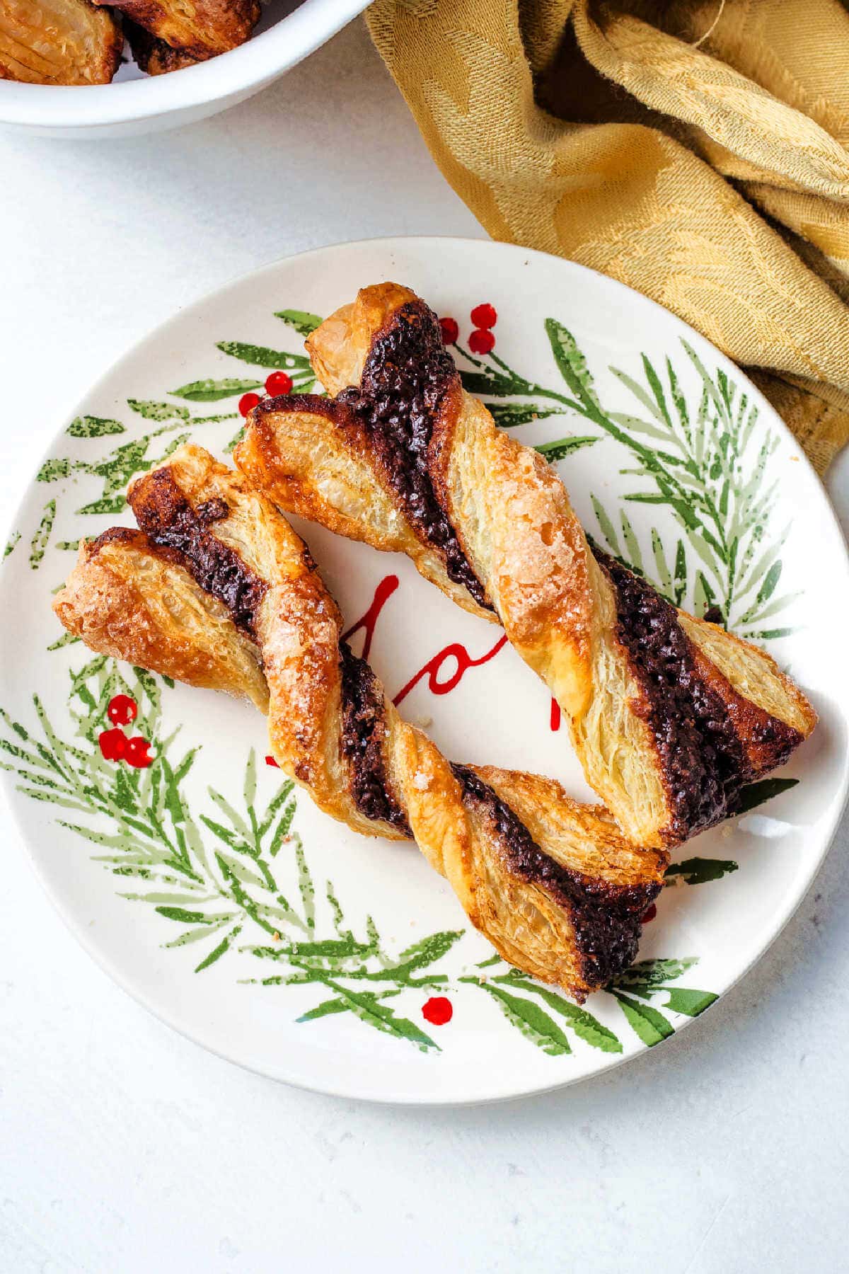 Two chocolate twists on a plate on a table with a gold napkin.