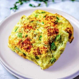 Two ricotta herb scones on a plate on a table.