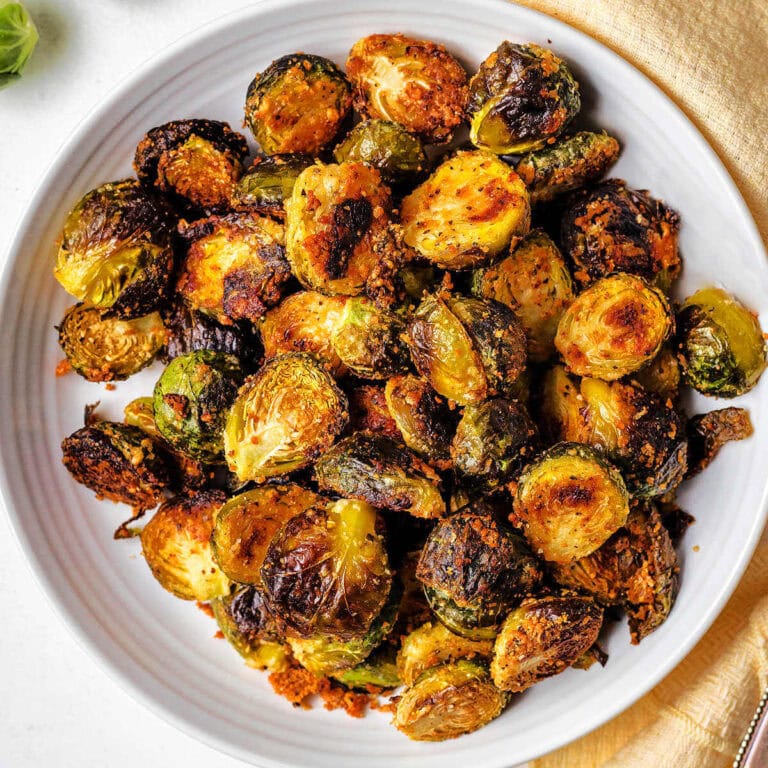 Brussels Sprouts with Parmesan in a serving bowl with a napkin on a table.