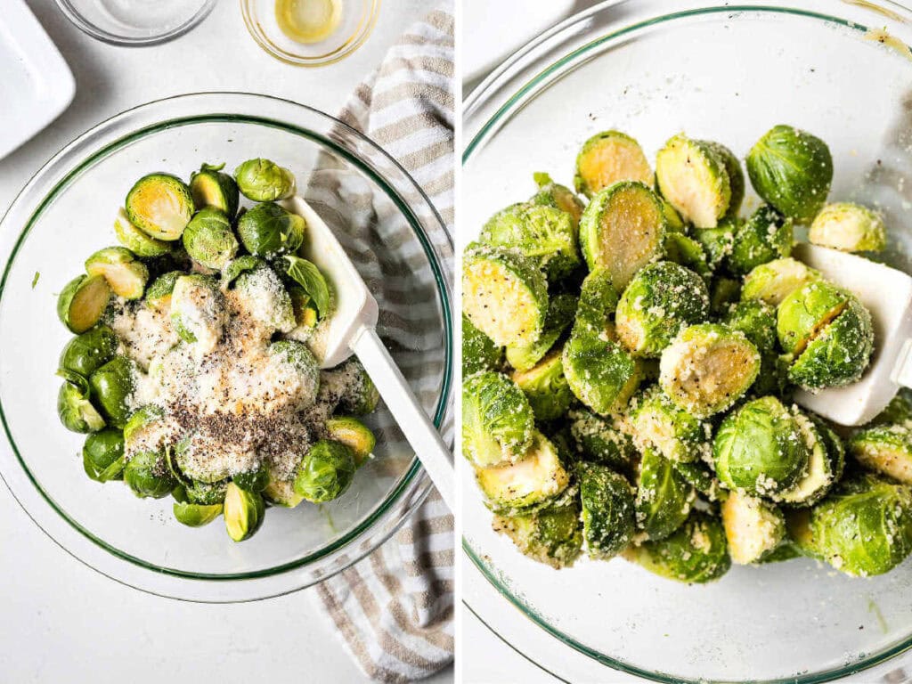 Brussels sprouts in a glass bowl being tossed with olive oil, Parmesan cheese, and spices using a rubber spatula.