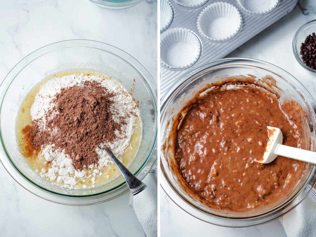 Adding flour and cocoa powder to batter for chocolate banana muffins in a glass bowl and stirring with a spatula.