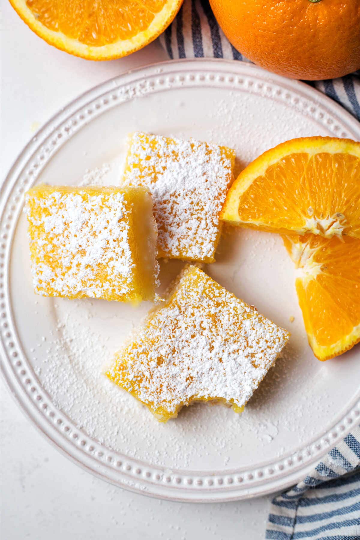 Orange bar with a bite missing on a plate on a table.