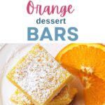 Orange bars stacked on top of each other on a plate with orange slices and powdered sugar dusted on top.