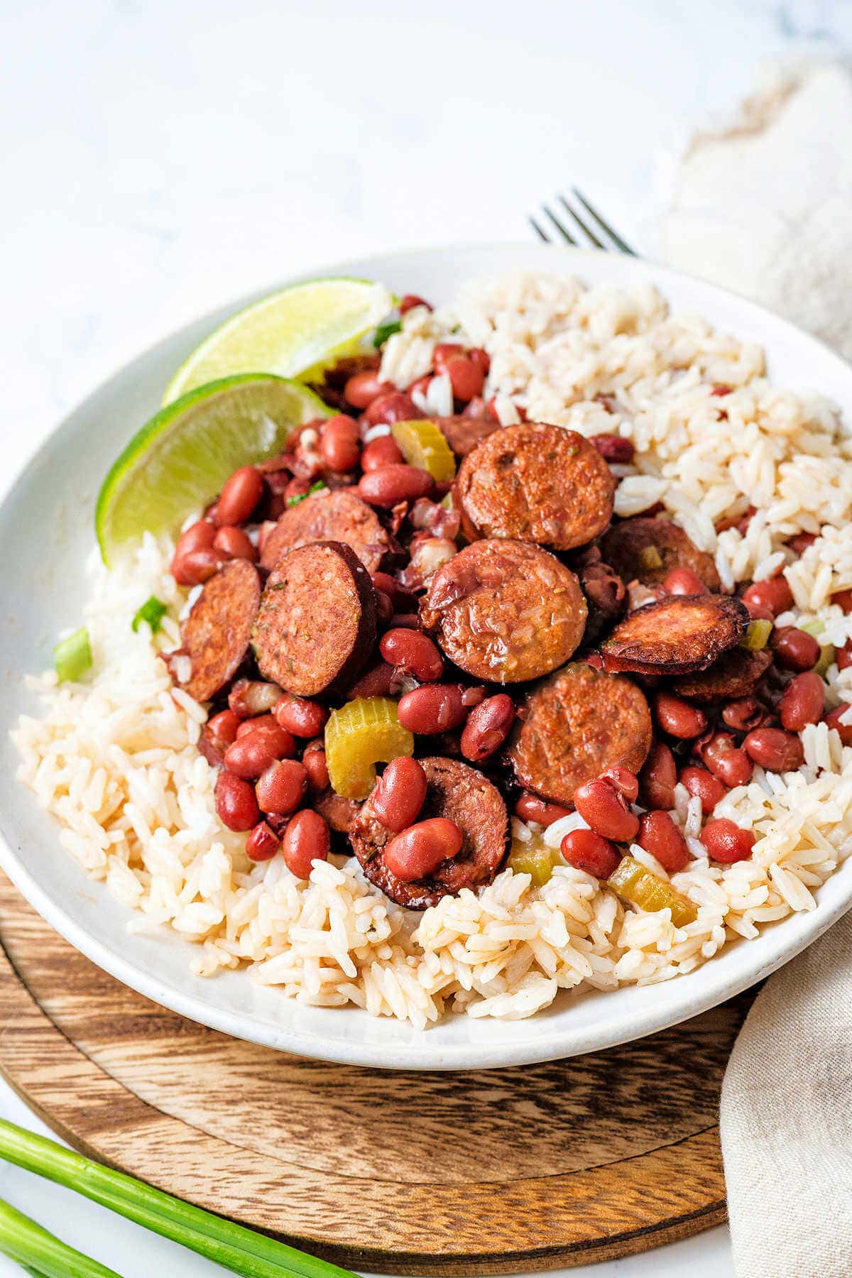 A bowl of red beans and rice on a wooden charger on a table.