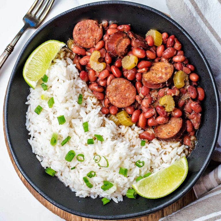 A bowl of red beans and rice on a table with a fork and napkin to the side.