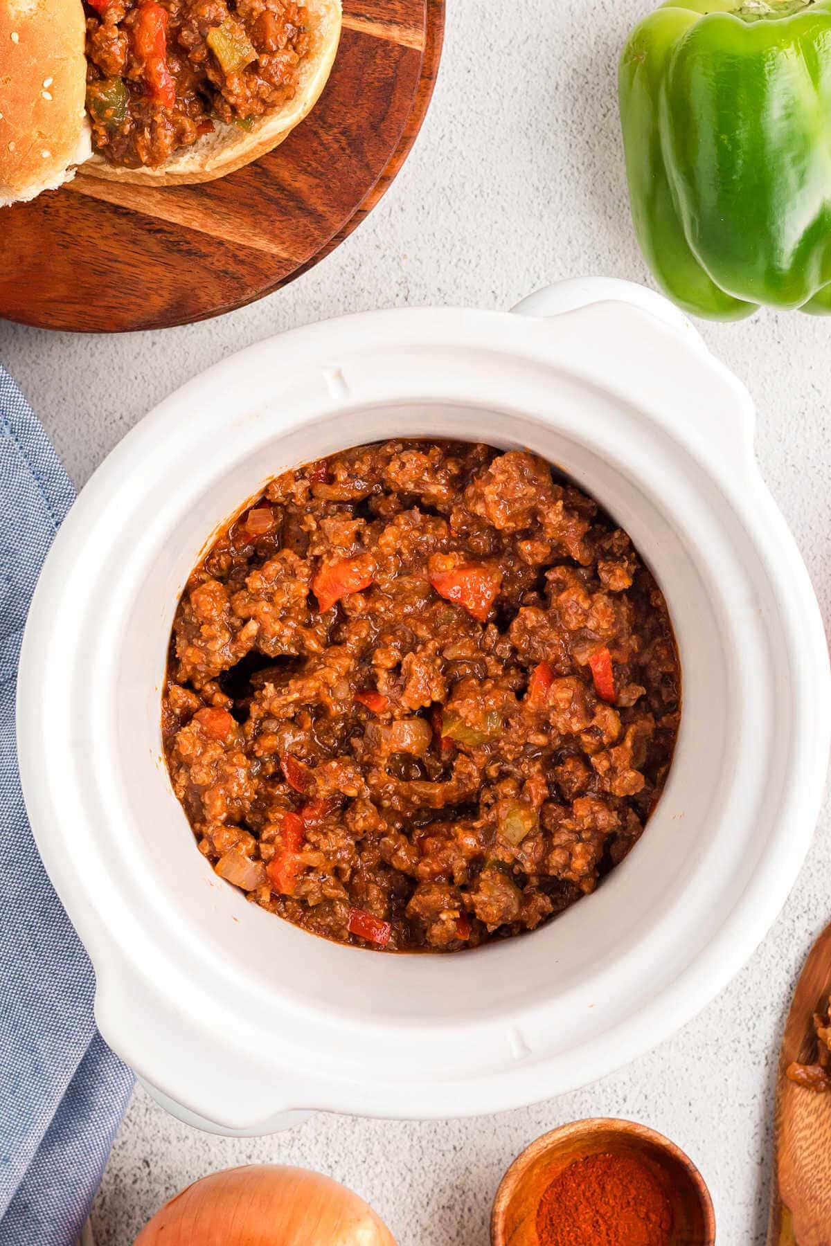 SloppY Joe sandwich meat in a slow cooker on a table with toppings.