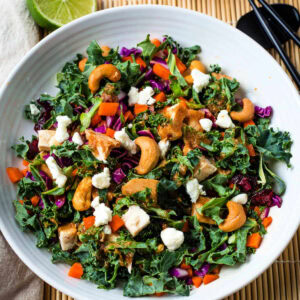 Chicken and Kale Salad in a bowl drizzled with Thai Peanut Dressing.