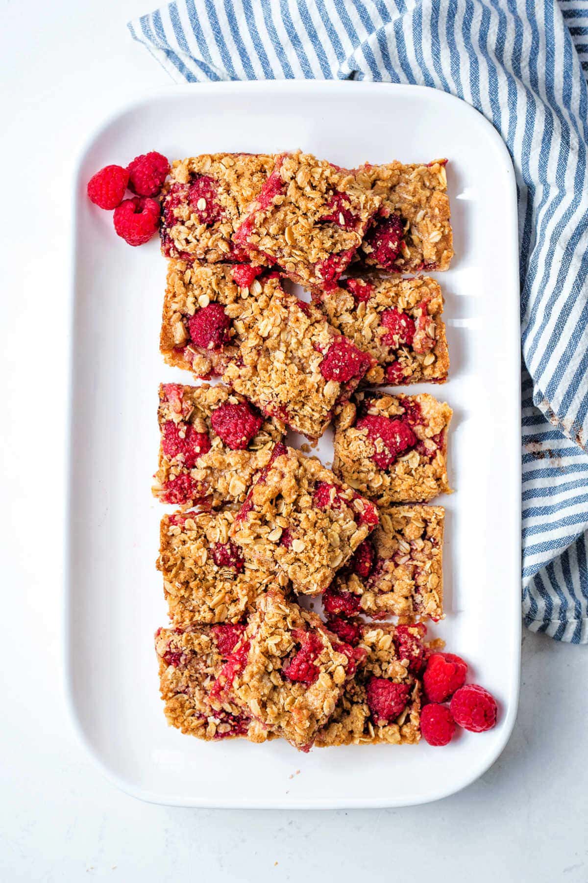 A platter of raspberry bars on a table with a napkin to the side.