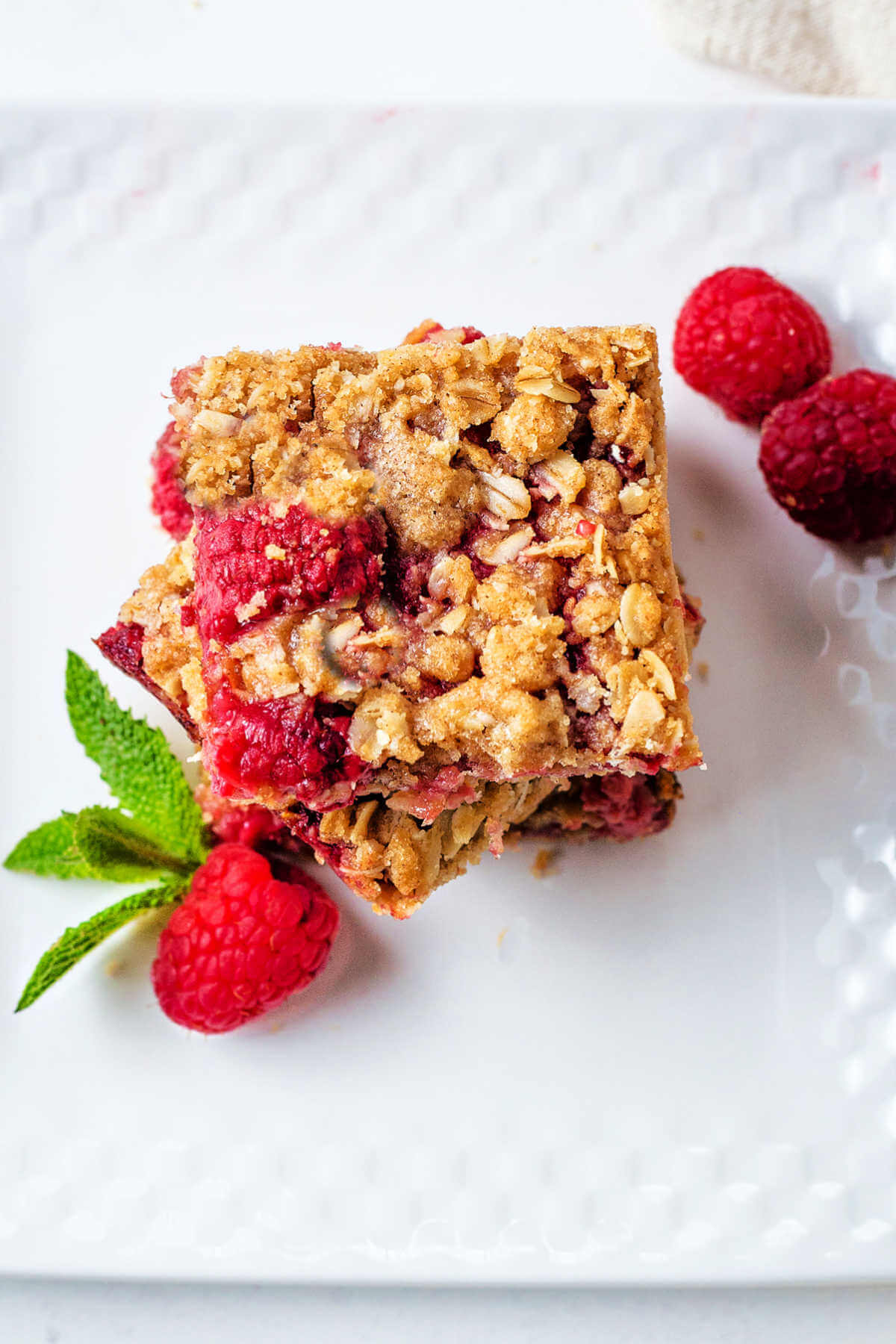 Top down view of raspberry bar on a plate with fresh mint and fresh raspberries.