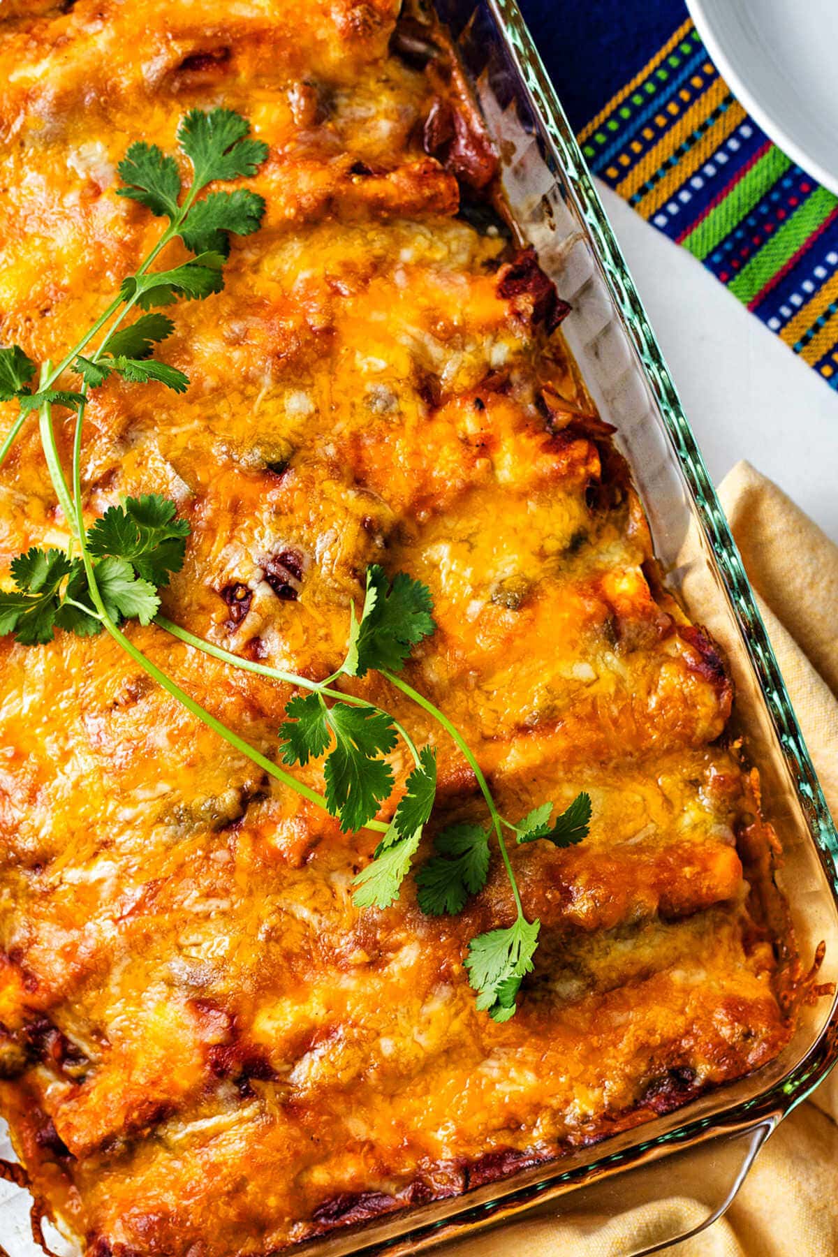 Overhead shot of chicken and black bean enchiladas in a glass baking dish.