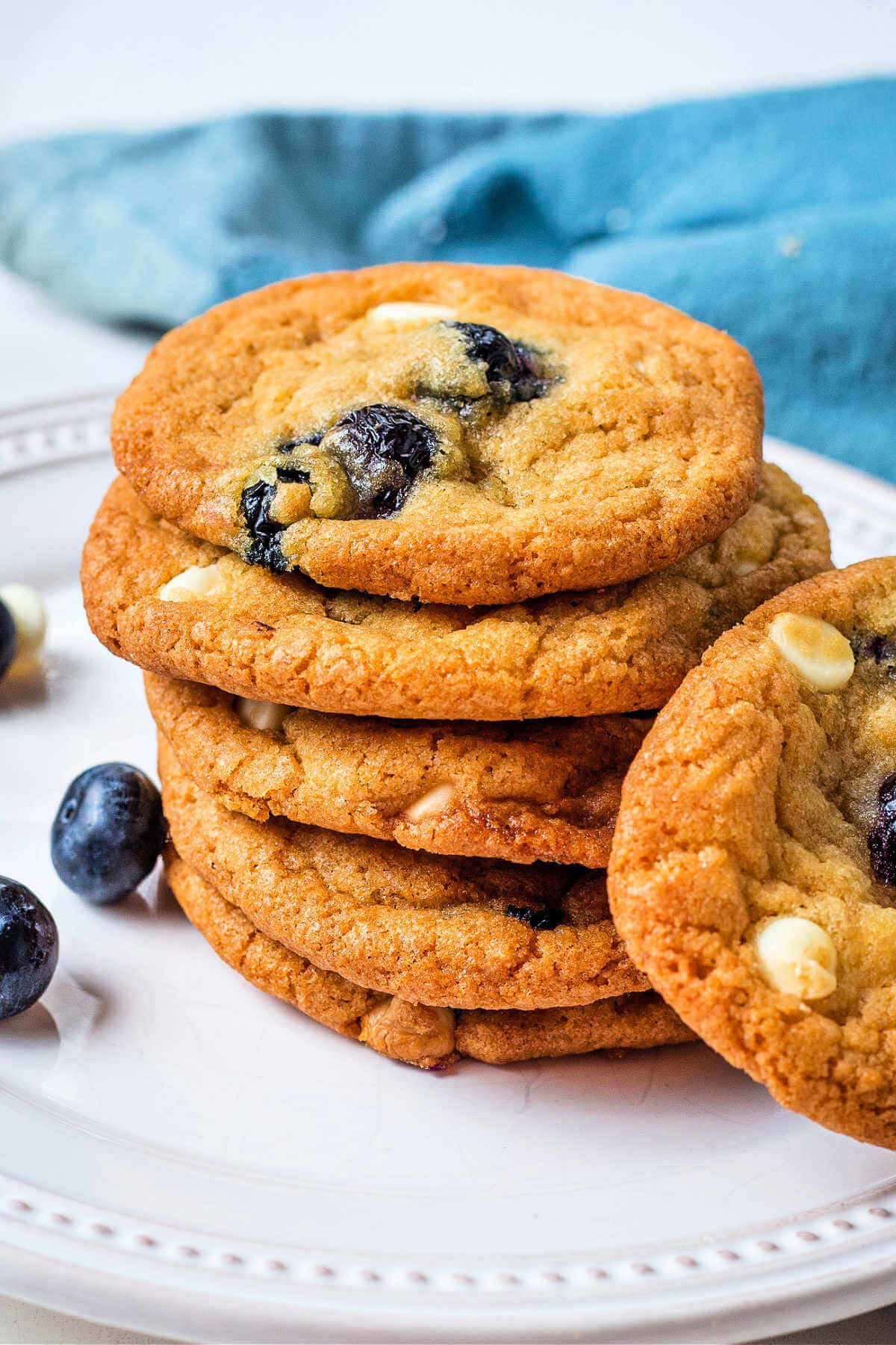 Stack of blueberry cookies with white chocolate chips on a plate.