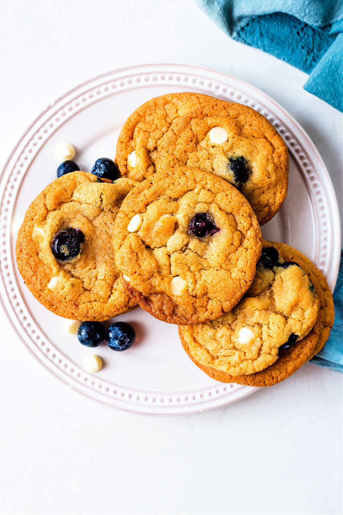 Pile of blueberry white chocolate cookies on a plate.