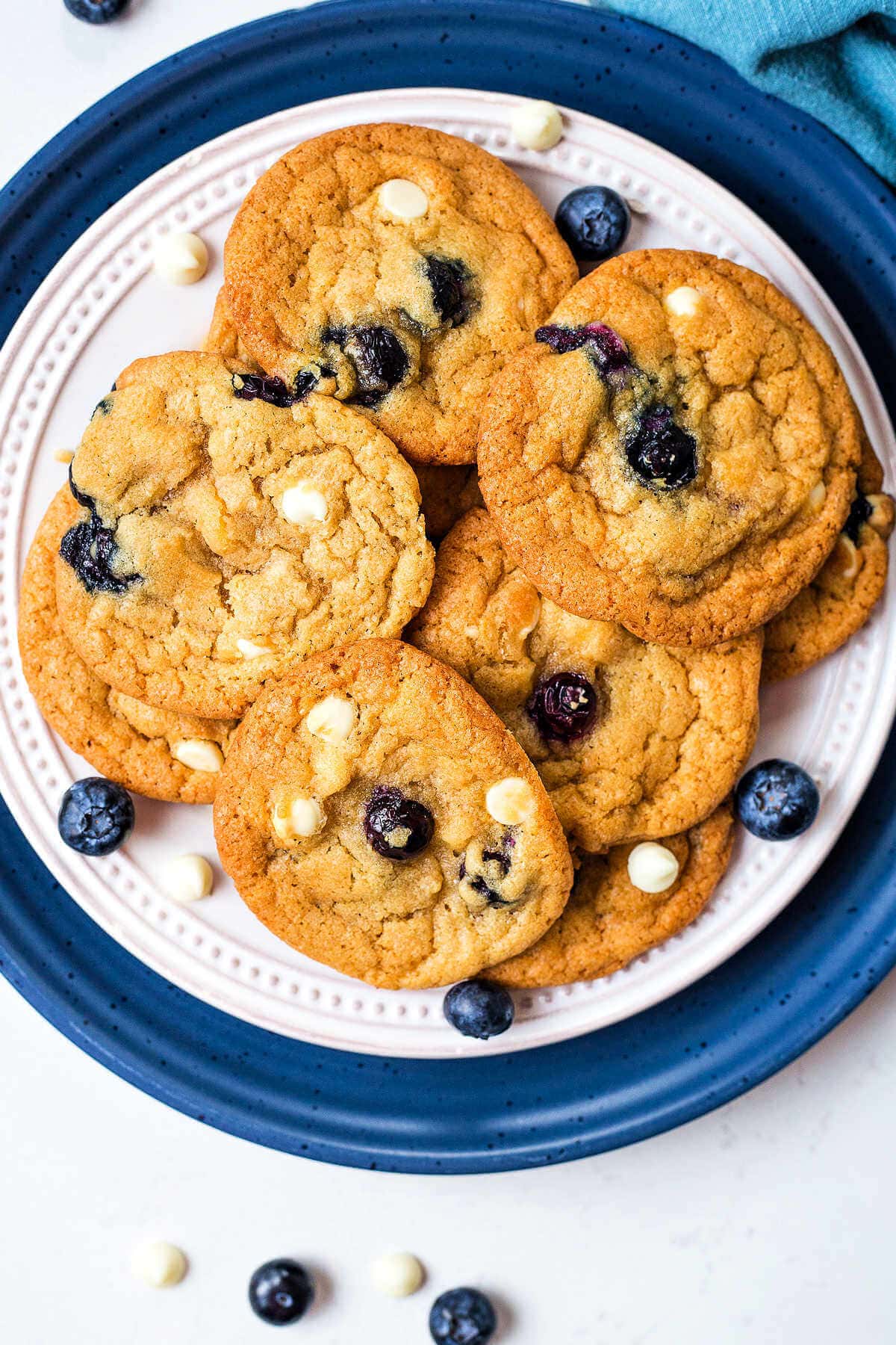 Overhead shot of a pile of blueberry cookies on a white plate.