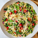Greek Orzo Pasta Salad with olives, tomatoes, red onion, and bell pepper in a bowl.