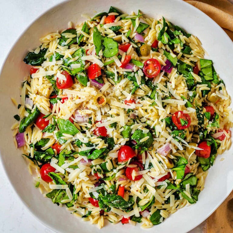 Greek Orzo Pasta Salad with olives, tomatoes, red onion, and bell pepper in a bowl.