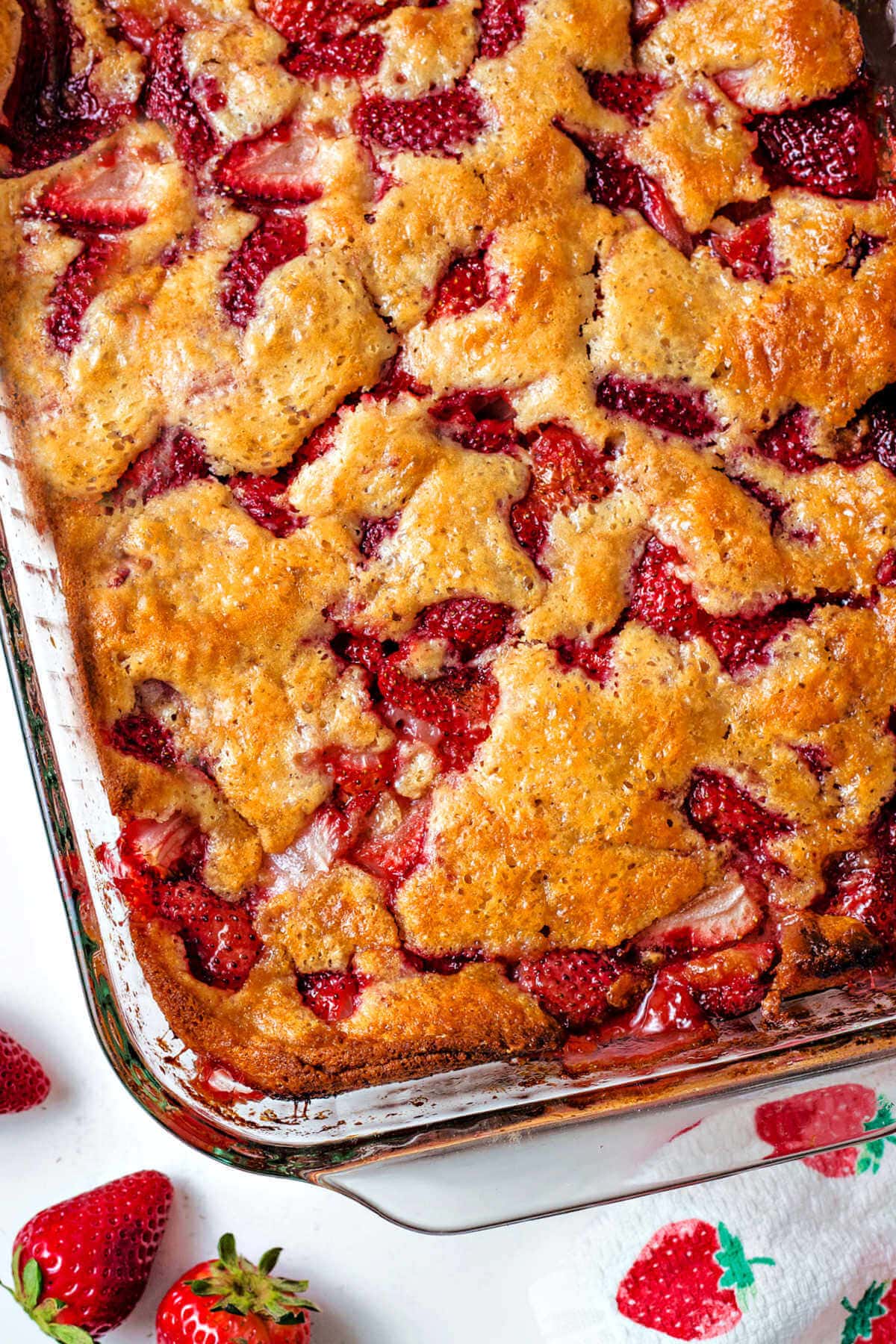 Corner of the baking dish of fresh strawberry cobbler.
