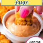 Hand dipping a chicken nugget into a ramekin of chickfil-A sauce.