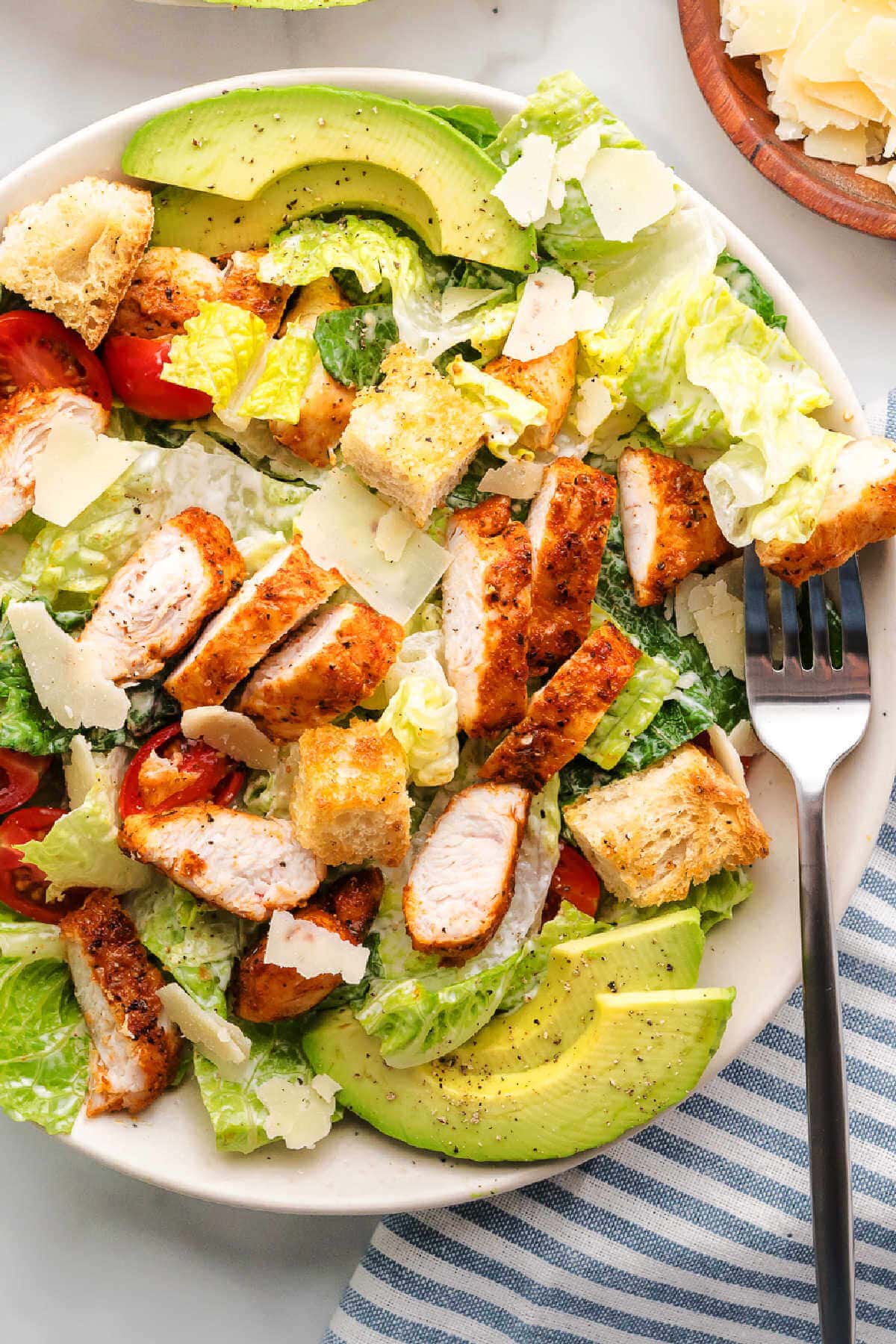 A serving of Blackened Chicken Caesar Salad on a plate with a fork to the side.