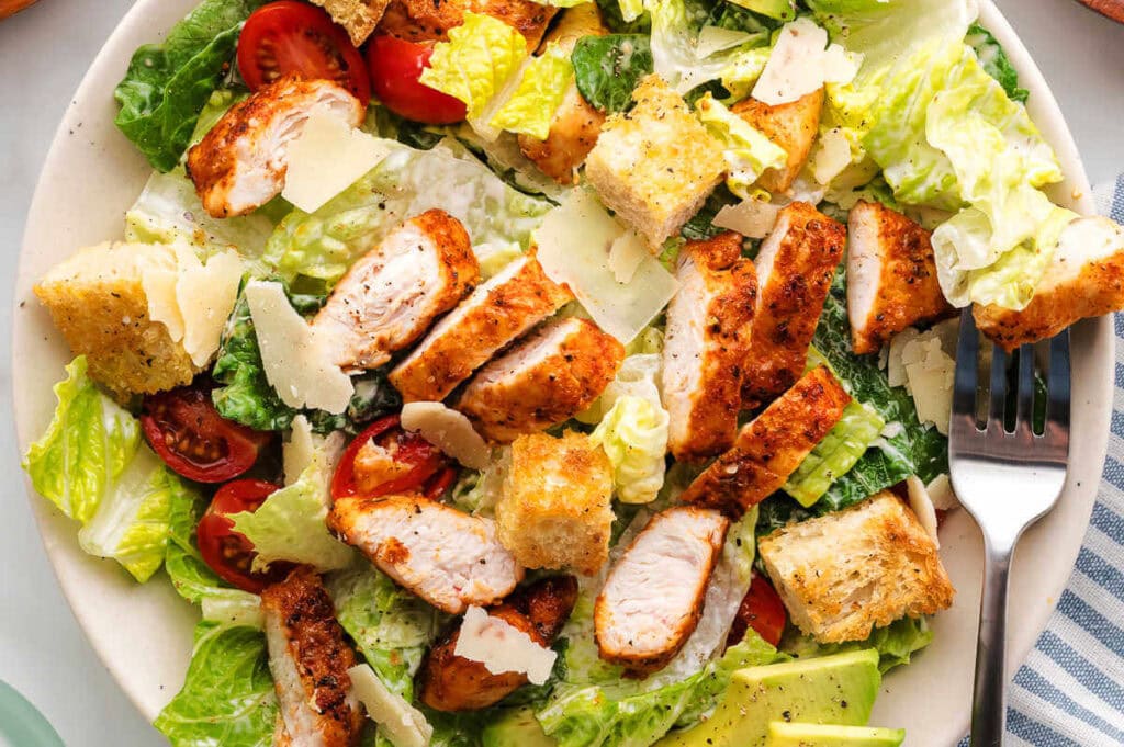 Horizontal image of chicken Caesar salad on a plate.