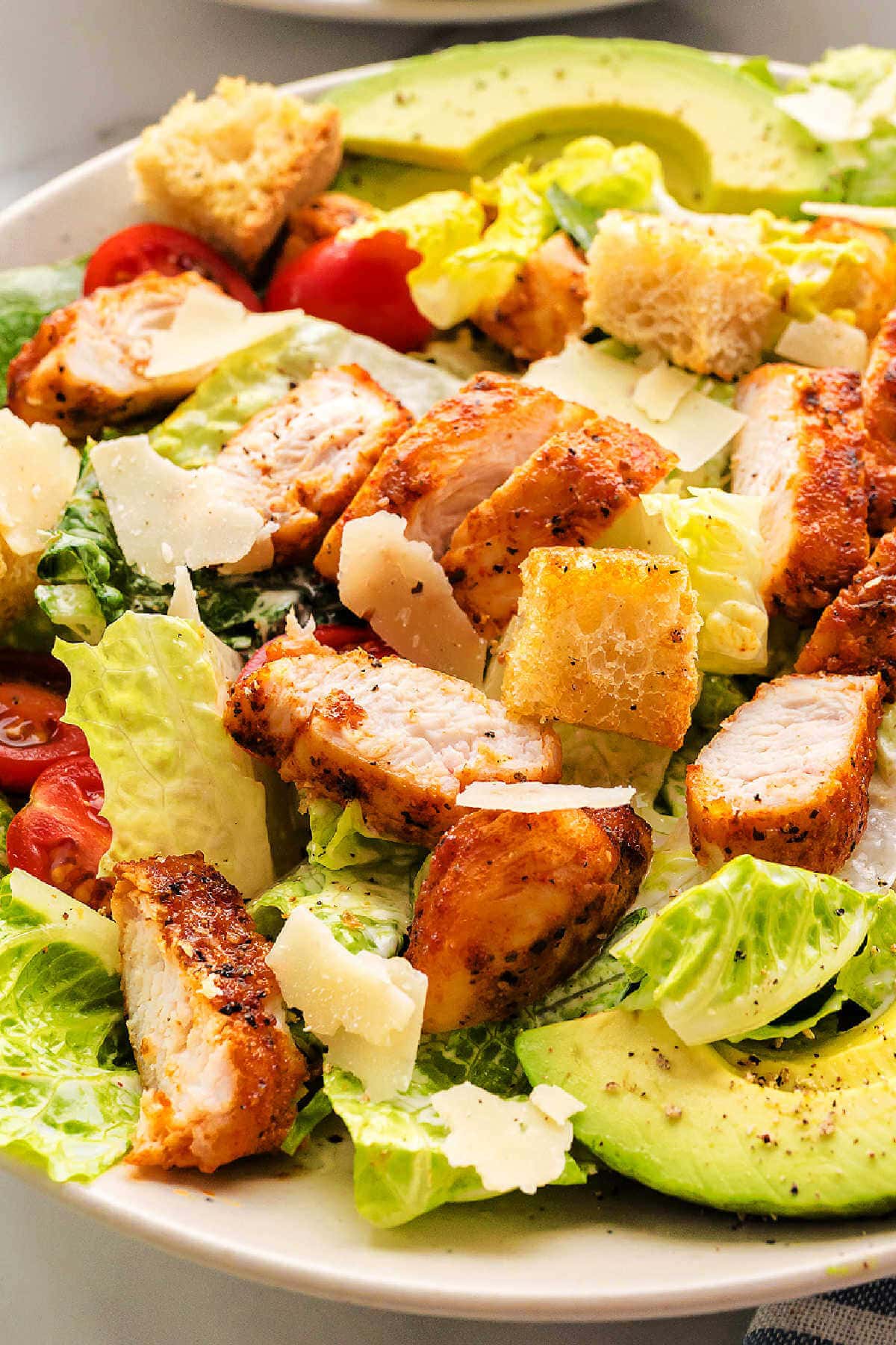 Close up image of blackened chicken on a bed of romaine lettuce on a plate.