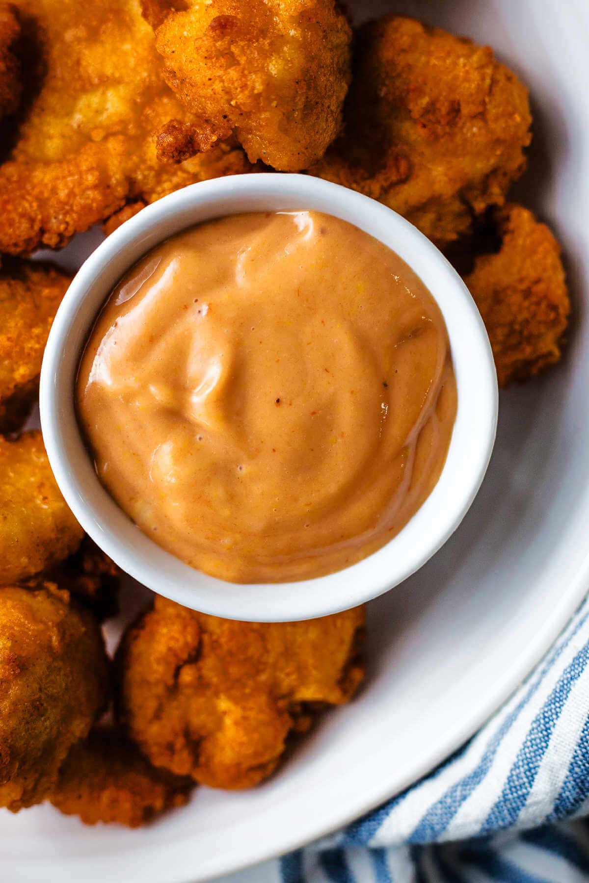 Chick Fil A sauce in a small bowl on a platter with chicken nuggets.