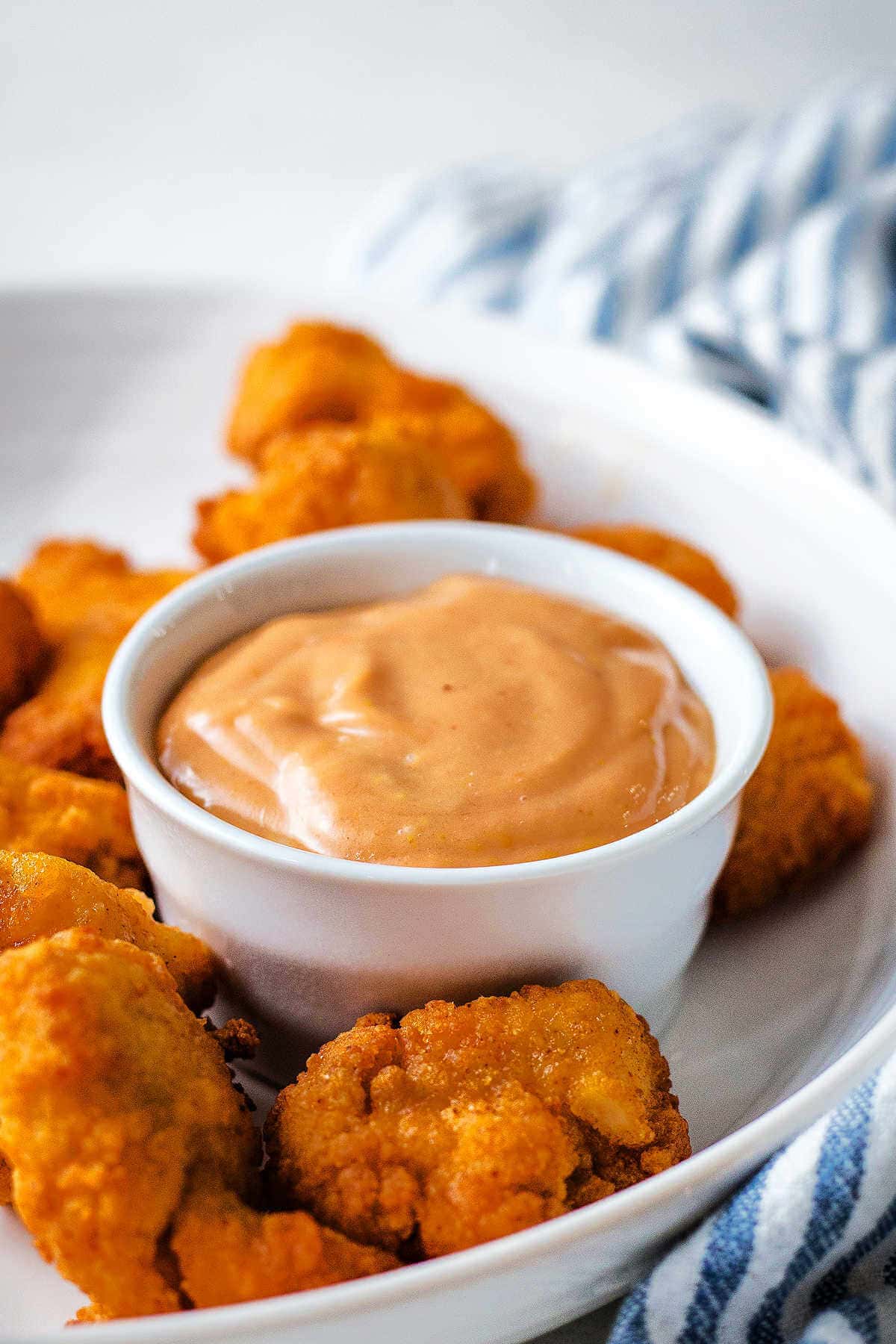 Chick Fil A sauce in a small bowl on a platter with chicken nuggets.