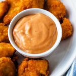 Chick Fil A sauce in a small bowl on a platter with chicken nuggets.