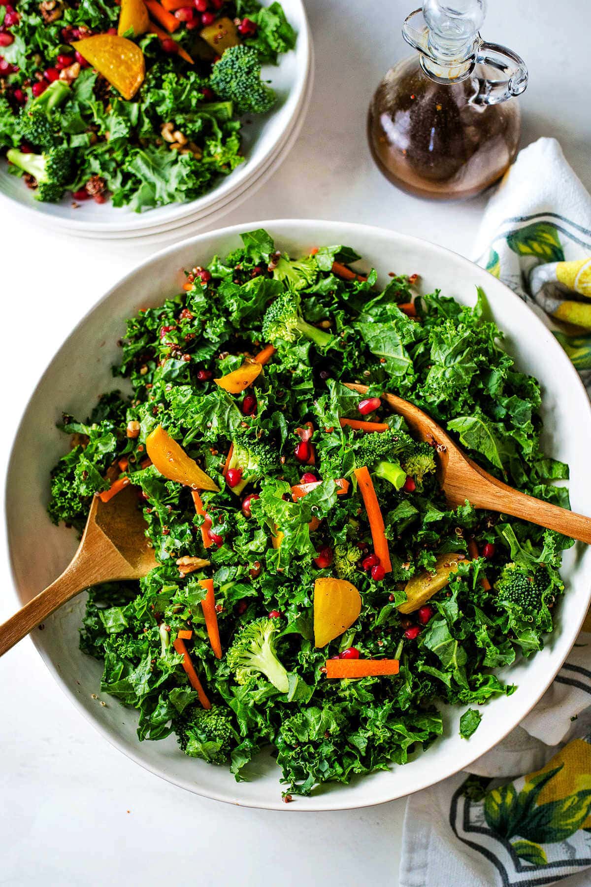 Super food salad with sesame ginger dressing in a large bowl with two wooden spoons.