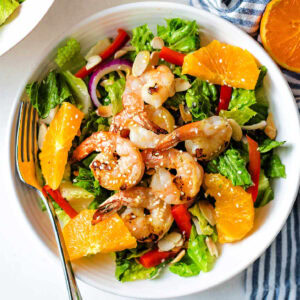Grilled Shrimp Salad with Citrus Vinaigrette in a bowl with orange slices and a fork to the side.